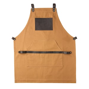 May include: A brown canvas apron with a large brown leather patch on the front. The apron has a large pocket on the front and adjustable straps.