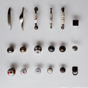 May include: Assortment of cabinet hardware, including pulls and knobs. The pulls are made of metal and have a variety of finishes, including silver, gold, and black. The knobs are made of ceramic and have a variety of designs, including floral, geometric, and abstract.