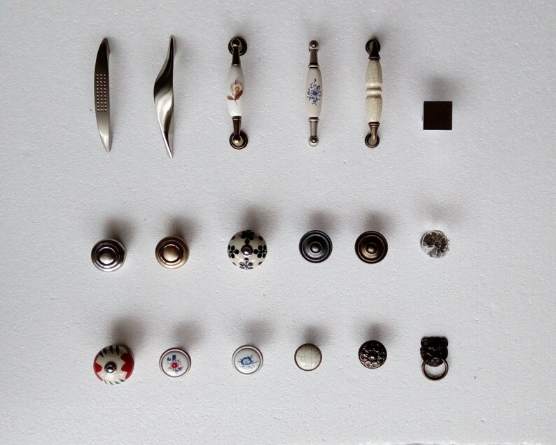 May include: Assortment of cabinet hardware, including pulls and knobs. The pulls are made of metal and have a variety of finishes, including silver, gold, and black. The knobs are made of ceramic and have a variety of designs, including floral, geometric, and abstract.