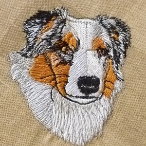 May include: Embroidered image of an Australian Shepherd dog with brown, white, and black fur. The dog is looking directly at the viewer.