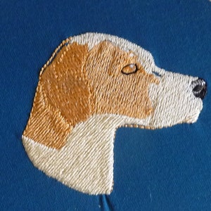 May include: Embroidered image of a dog's head, with white and brown fur, on a blue background.