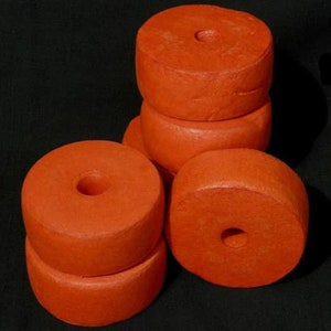 Op de afbeelding: Een stapel van vijf oranje schuimboeien met een gat in het midden van elk. De boeien zijn in een piramidevorm gestapeld.