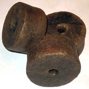 May include: Three brown, round, wooden objects with a hole in the centre. The objects are stacked on top of each other.