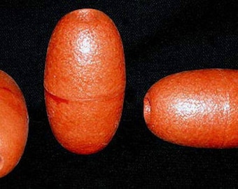 May include: Three orange, oblong fishing floats. Two are upright, and one is horizontal. Each has a hole at one end. The floats are made of a textured material and are set against a black background.