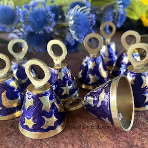 May include: A set of eight small brass bells with a blue and gold enamel design. The bells have a crescent moon and star pattern.