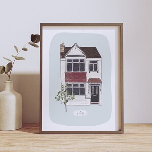 Op de afbeelding: Een ingelijste illustratie van een huis met twee verdiepingen met een rode bakstenen gevel, zwarte ramen en een zwarte deur. Het huis heeft een kleine boom ervoor en de tekst "J&B" eronder.