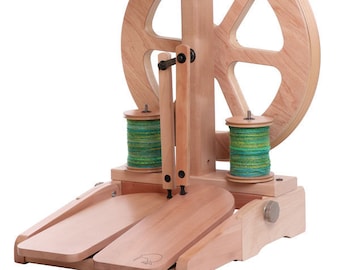 May include: A wooden spinning wheel with a large wheel and two smaller bobbins. The wheel is made of light wood and has a natural finish. The bobbins are also made of wood and are painted green. The spinning wheel is sitting on a wooden base.