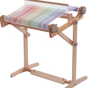 Peut inclure: Un métier à tisser en bois avec une tapisserie tissée aux couleurs de l'arc-en-ciel. Le métier à tisser est sur un support avec une base en bois.