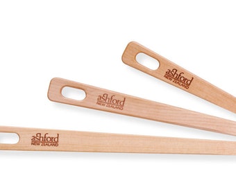 Puede incluir: Tres agujas de tejer de madera con un agujero en el medio y el texto "Ashford Nueva Zelanda" impreso en ellas.