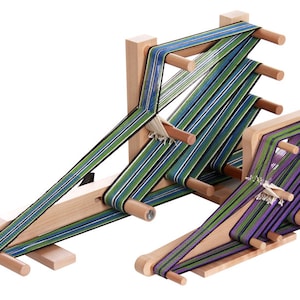May include: A wooden loom with two sets of spools, each with a different coloured striped fabric being woven. The loom is made of natural wood and has a simple design.