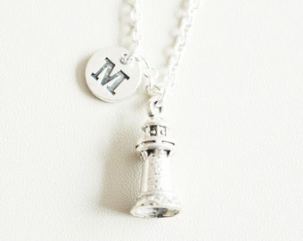 May include: A silver necklace with a lighthouse charm and a silver disc charm with the letter "M" engraved on it.