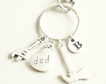 Op de afbeelding: Zilveren sleutelhanger met een hartvormige hanger met de tekst "dad", een moersleutel hanger, een hamer hanger en een ronde hanger met de letter "B".