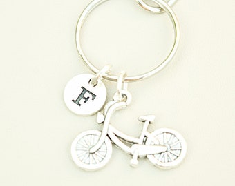 May include: Silver bicycle keychain with a silver charm with the letter F.