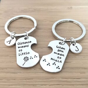 May include: Two silver keychains with matching puzzle pieces. One piece says "Distance means so little" with a dandelion and the other says "When you mean so much".
