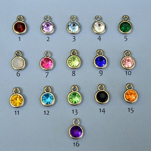 May include: Assortment of 16 small round charms with different colored rhinestones. The charms are gold-toned and have a loop at the top for attaching to jewelry or other crafts.