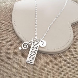 May include: Silver necklace with a piano key charm, a treble clef charm, and a silver charm with the letter "P" on it.