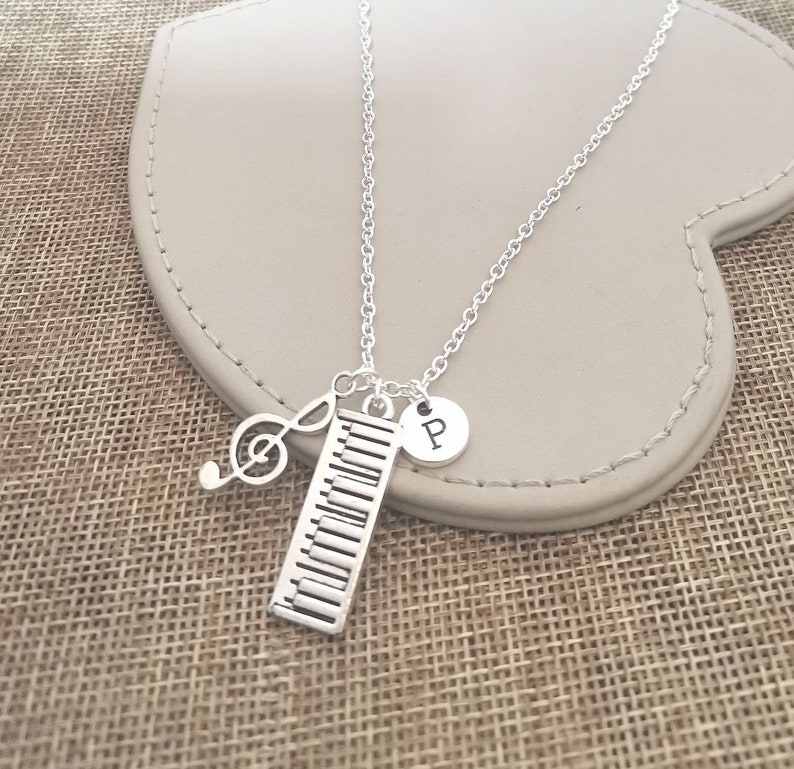 May include: Silver necklace with a piano key charm, a treble clef charm, and a silver charm with the letter "P" on it.