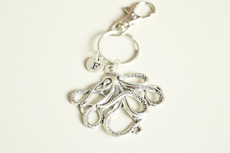 May include: Silver octopus keychain with a silver letter 'F' charm attached to a silver key ring.
