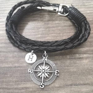 May include: Black leather bracelet with a compass charm and a silver charm with the letter H.