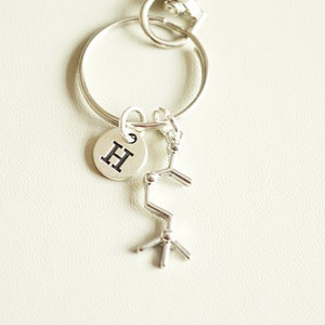 Puede incluir: Llavero de plata con un pequeño dije redondo con la letra H y un dije con forma de molécula química.