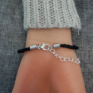 Puede incluir: Un brazalete trenzado negro con un cierre plateado y una extensi&oacute;n de cadena.