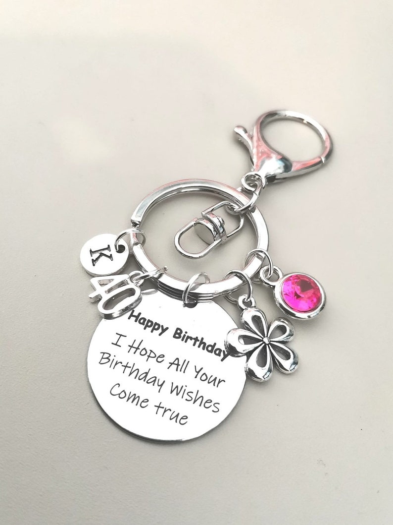 May include: Silver keychain with a pink rhinestone, a silver flower charm, and a round charm that says "Happy Birthday I Hope All Your Birthday Wishes Come True".