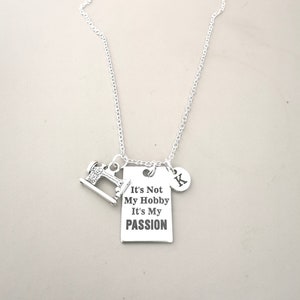 May include: Silver necklace with a sewing machine charm and a rectangular tag that reads "It's Not My Hobby It's My Passion". The necklace also has a charm with the letter "K" on it.