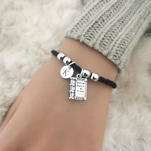 May include: Black leather bracelet with silver beads and a charm that says "Once Upon A Time" and a silver charm with the letter K.