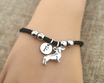 May include: A black leather bracelet with silver beads and a silver charm of a dachshund and a silver charm with the letter F.