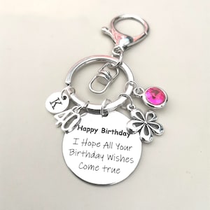 May include: Silver keychain with a pink rhinestone, a silver charm with a flower design, and a round charm with the text "Happy Birthday I Hope All Your Birthday Wishes Come True".