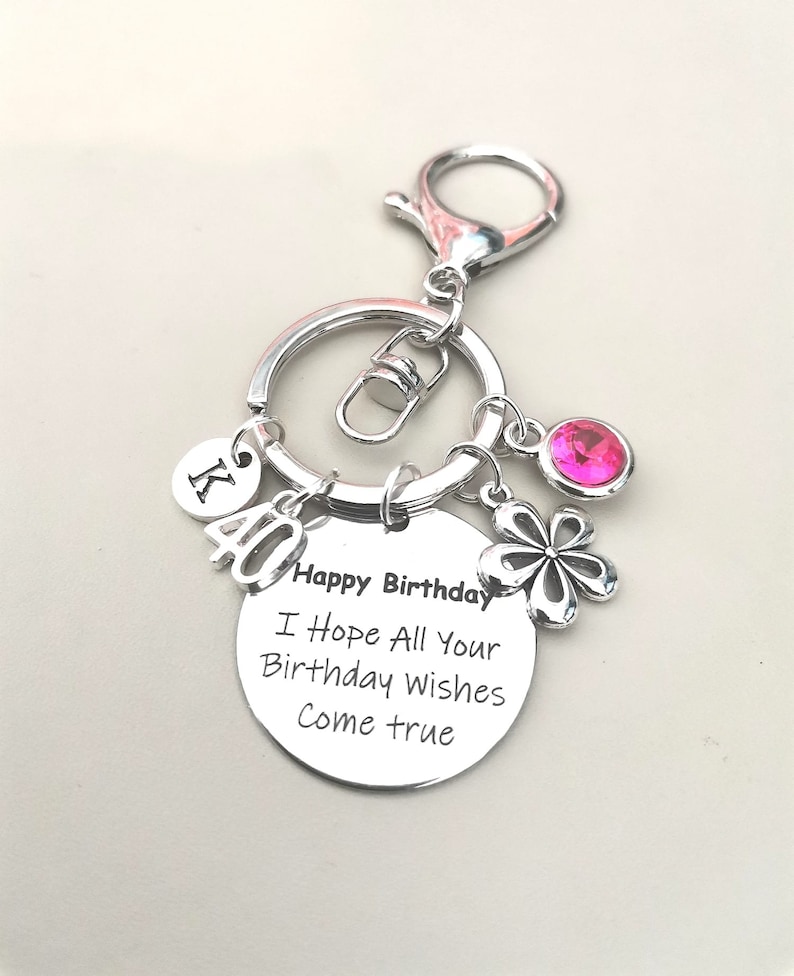 May include: Silver keychain with a pink rhinestone, a silver charm with a flower design, and a round charm with the text "Happy Birthday I Hope All Your Birthday Wishes Come True".