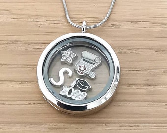 Puede incluir: Collar con dije de plata con temática de graduación. El dije contiene dijes que incluyen una estrella, un gorro de graduación, un diploma y la letra "S" con el año "2023" en pedrería.