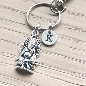 Puede incluir: Llavero de plata con un dije de Ganesha detallado y un pequeño dije de plata con la letra K.
