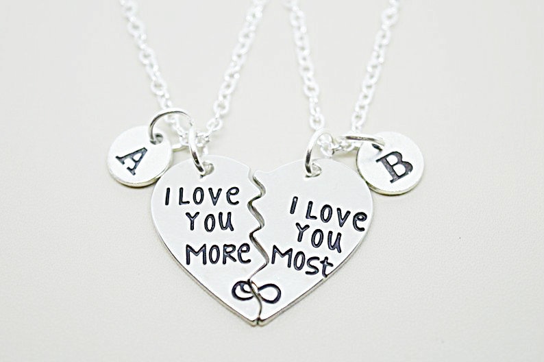 May include: Two silver necklaces with matching heart pendants that say "I love you more" and "I love you most". The hearts are broken in half and fit together. Each necklace has a small round charm with the letters "A" and "B" on them.