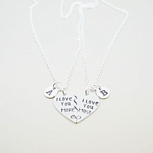 May include: Two silver necklaces with matching heart pendants that say "I love you more" and "I love you most". Each pendant has a small circle charm with the letter "A" and "B" on them.