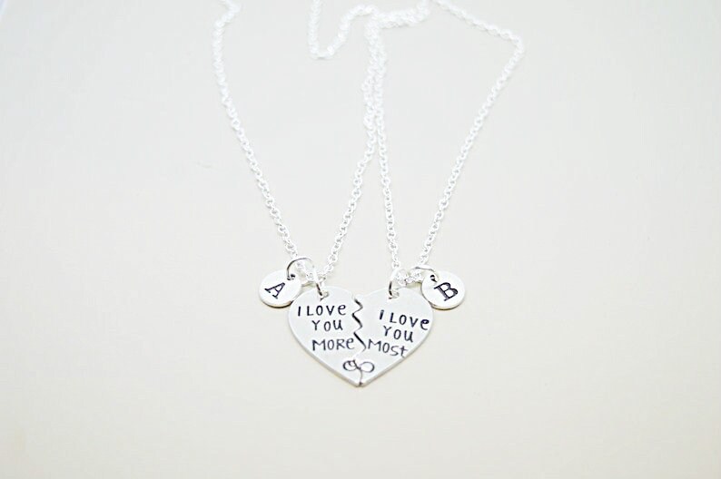 May include: Two silver necklaces with matching heart pendants that say "I love you more" and "I love you most". Each pendant has a small circle charm with the letter "A" and "B" on them.