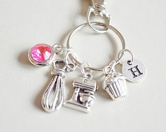 May include: Silver keychain with a pink rhinestone, a cupcake charm, a mixer charm, a whisk charm, and a charm with the letter H.