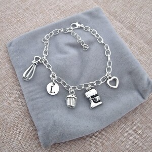 May include: Silver charm bracelet with a heart, cupcake, mixer, whisk, and initial L charm.