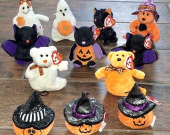 May include: A collection of Halloween-themed plush toys, including ghosts, bats, bears, and pumpkins. The toys feature vibrant colors like orange, black, purple, and white, with some wearing witch hats. The plushies are designed with festive details.