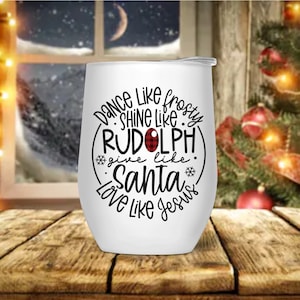 May include: White wine tumbler with a black and red design that says "Dance like Frosty, Shine like Rudolph, Give like Santa, Love like Jesus".