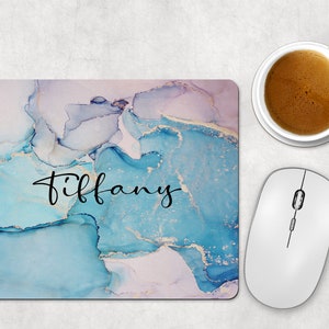 May include: A blue and white marble mouse pad with the name "Tiffany" written in black cursive.