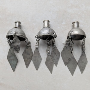 May include: Three silver-toned metal ornaments, each featuring a dome-shaped top with a small cylindrical neck and multiple dangling diamond-shaped metal charms attached by small circular jump rings. The metal has a matte, weathered finish.