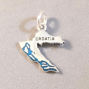 May include: A silver charm depicting the outline of Croatia, with blue enamel highlighting the coastline. The word "CROATIA" is inscribed at the top. The charm has a loop for attaching to jewellery.