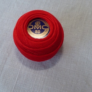 May include: A red ball of DMC embroidery floss with a gold label that says "DMC 80 Mouliné Special Cotton Embroidery Floss".