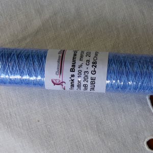 Può includere: Un'bobina di filo di cotone blu chiaro etichettata "Frank's Baumwol Cotton 100% merce NeB 20/3 - ca. 200 TAUBE G-28/Charp"