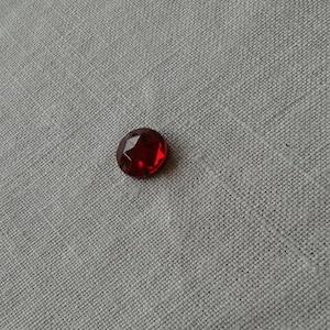Peut inclure: Une seule pierre précieuse rouge ronde avec une taille facetée.