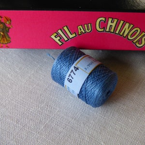 Puede incluir: Una bobina de hilo de bordar azul con el n&uacute;mero 6774 impreso en la etiqueta. La etiqueta tambi&eacute;n dice "Fil au Chinois" y "J. Touche".