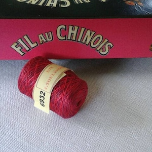 Può includere: Un'bobina di filo da ricamo rosso con un'etichetta bianca che recita "FIL AU CHINOIS" e "6932".