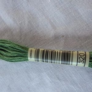 May include: A skein of green embroidery floss with a white label that reads "320" and a barcode. The label also has the number "1236039Y" printed on it.