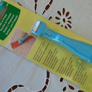 Peut inclure: Outil bleu Clover Roll & Press pour presser les coutures ou les plis dans le tissu ou le papier. L'outil est ergonomique et portable. L'emballage comprend des instructions en anglais, français, espagnol, allemand et portugais.